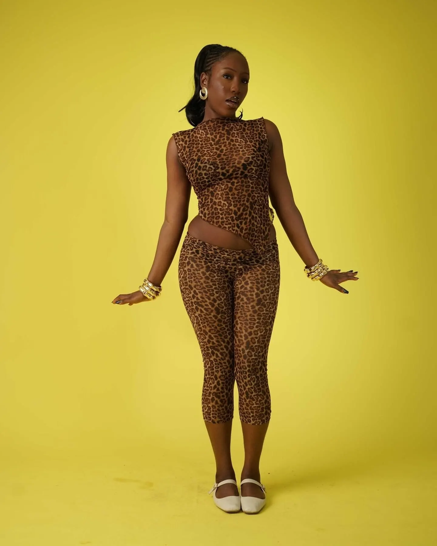 Model in a matching leopard-print mesh top and leggings, arms open, wearing cream Mary Jane flats.