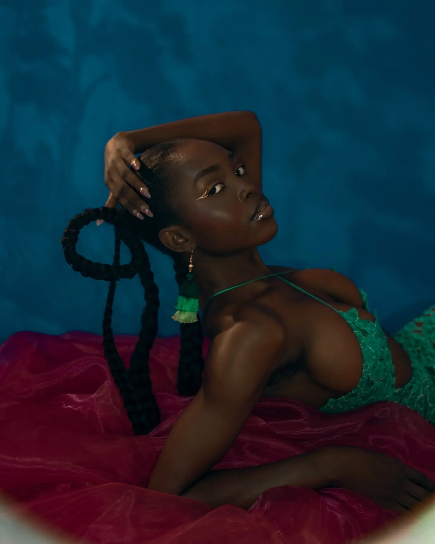 Lying back on pink tulle, Uyi cradles her head as long braids spill in loops beside her.