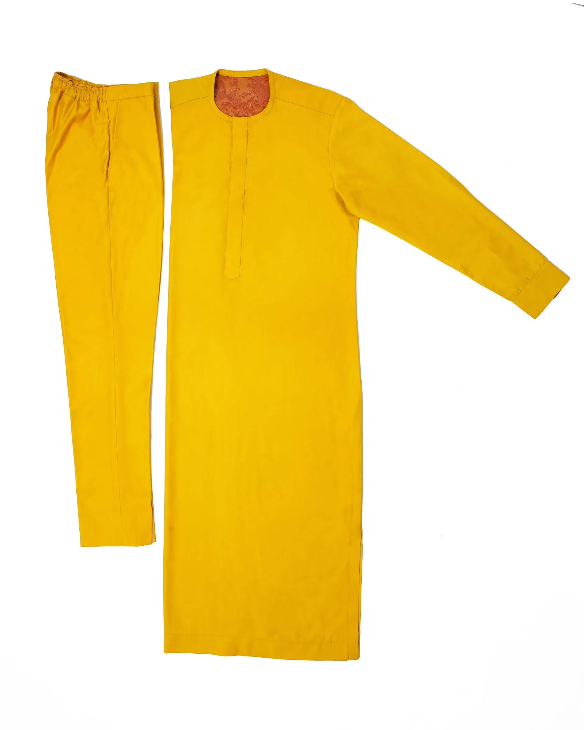 A yellow kaftan and matching trousers laid flat on a white surface.