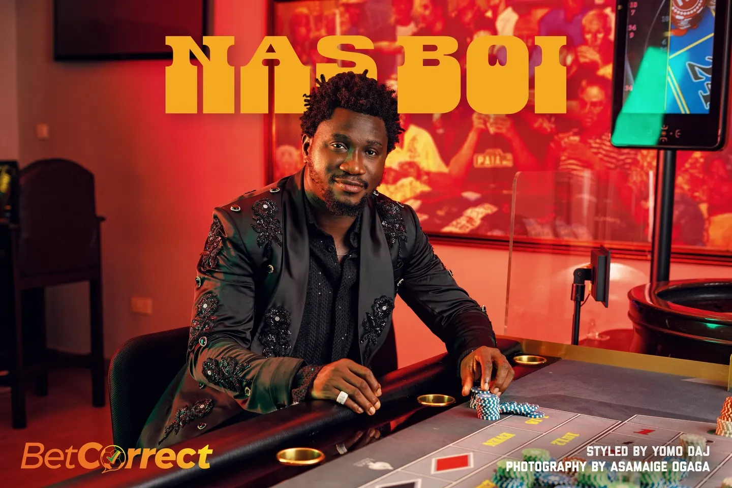 NAS BOI title card — the comedian in an embroidered black suit seated at a roulette table stacked with chips, arcade screens glowing red behind, BetCorrect mark in the corner.